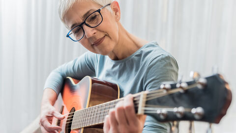 Frau übt Gitarre spielen