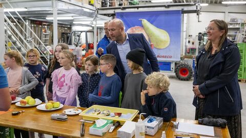 Umweltminister Jung schaut gemeinsam mit Schülerinnen und Schüler auf einen Tisch. Auf dem Tisch befinden sich Äpfel in verschiedenen Zuständen.