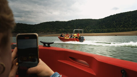 Eine Person fotografiert mit einem Handy ein Boot.