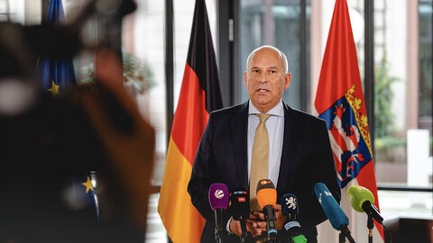 Innen- und Heimatschutzminister Roman Poseck Wirtschaftsminister Mansoori steht vor Mikrofonen in einer Interviewsituation.