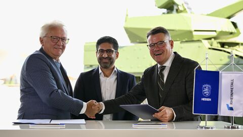 Zwei Herren geben sich die Hand und schauen in die Kamera.