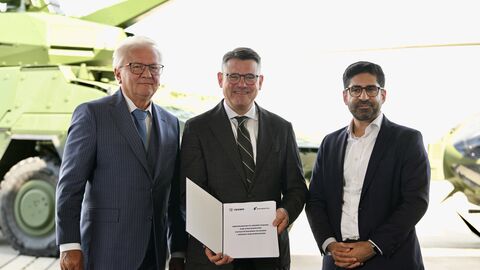 Drei Herren halten einen Vetrag in die Kamera. 