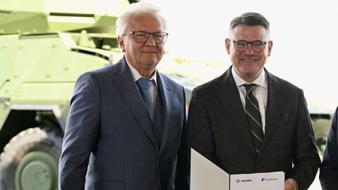 Zwei Herren halten einen Vertrag in die Kamera.