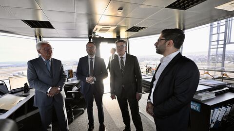 Eine Gruppe Menschen steht in einem verglasten Raum. 
