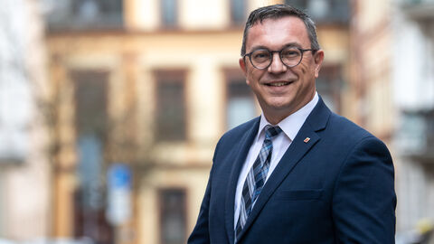 Mann mit Brille lächelt in Kamera.