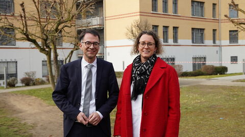 Ein Mann und eine Frau stehen nebeneinander vor einem Gefängnisgebäude